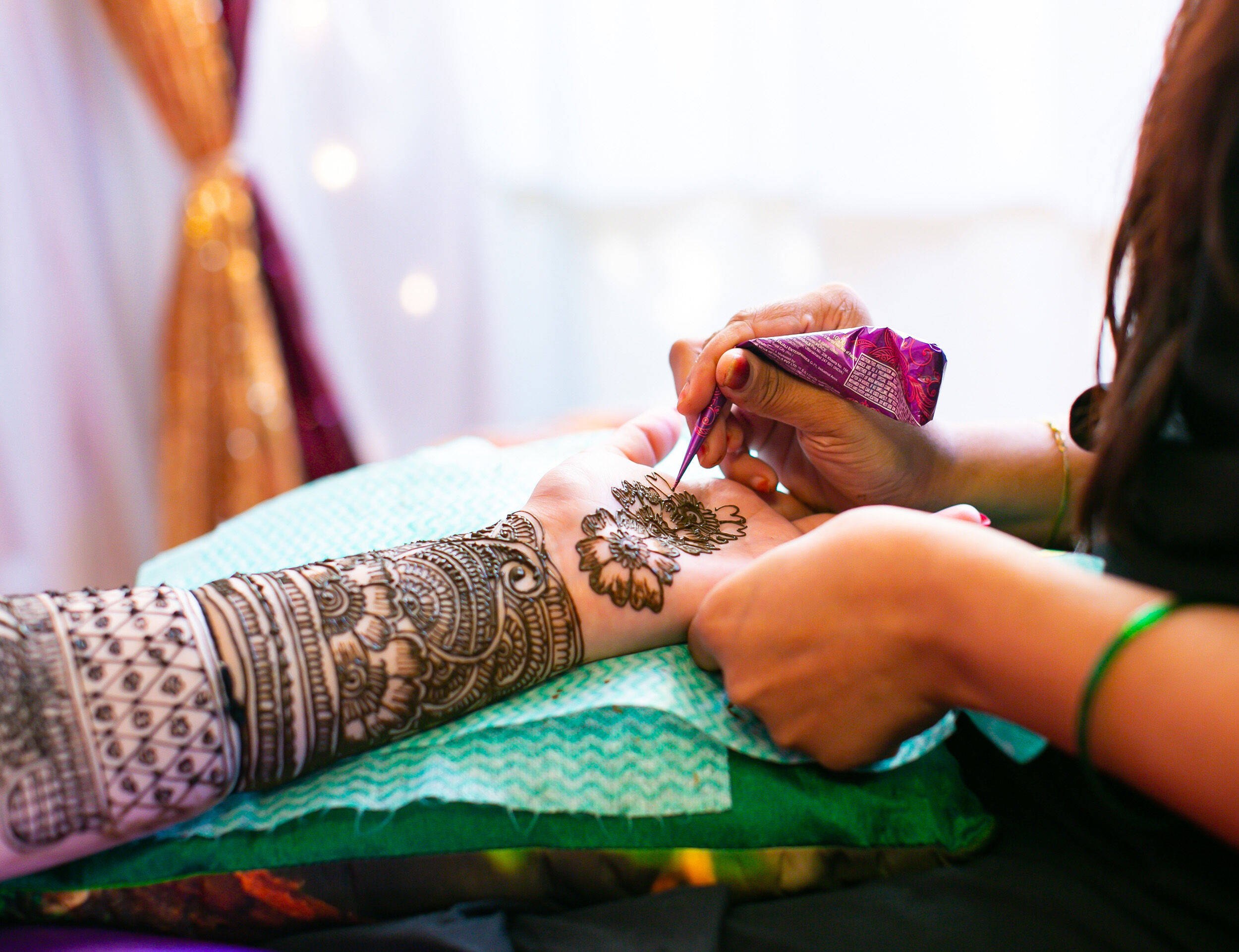 a girl getting mehendi done by a proffetional mehendi designer for a mehendi ceremony 